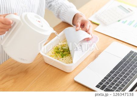 会社のデスクでカップ焼きそばを作るミドル女性の手元 126347138