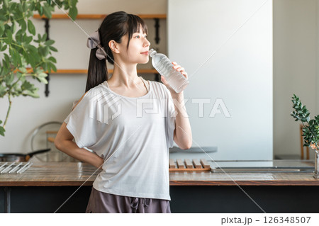自宅トレーニング後にペットボトルのミネラルウォーターで水分補給をするアジア人女性 126348507