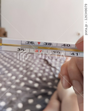 He holds a mercury thermometer in his hands with a high temperature. Illness malaise He holds a mercury thermometer in his hands with a high temperature. Illness malaise 126349079