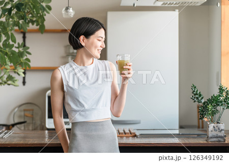 家・自宅のリビングでトレーニング後に水分補給,栄養補給する若いアジア人女性 126349192