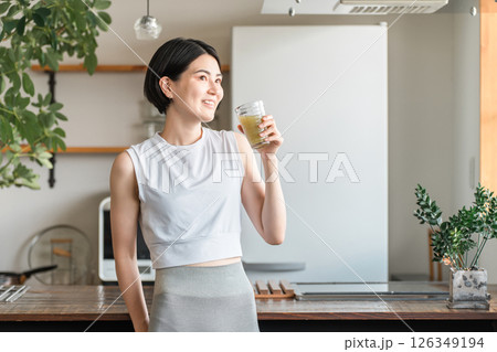 家・自宅のリビングでトレーニング後に水分補給,栄養補給する若いアジア人女性 126349194