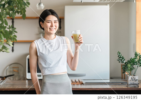 家・自宅のリビングでトレーニング後に水分補給,栄養補給する若いアジア人女性 126349195