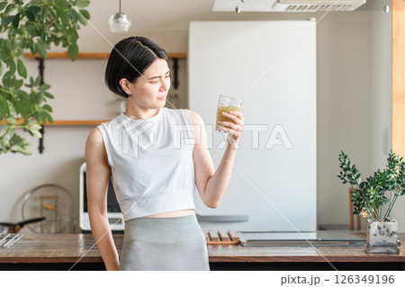 家・自宅のリビングでトレーニング後に水分補給,栄養補給する若いアジア人女性 126349196