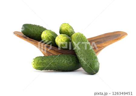 Collection of fresh, vibrant green cucumbers displayed in a rustic wooden bowl. Collection of fresh, vibrant green cucumbers displayed in a rustic wooden bowl. 126349451