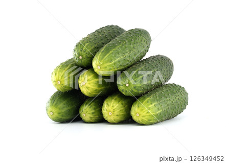 Neatly arranged pyramid of fresh, vibrant green cucumbers against a clean white backdrop. 126349452
