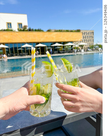 Hands holding chilled cocktails on pool background close-up, man and girl on vacation, travel Hands holding chilled cocktails on pool background close-up, man and girl on vacation, travel 126349486