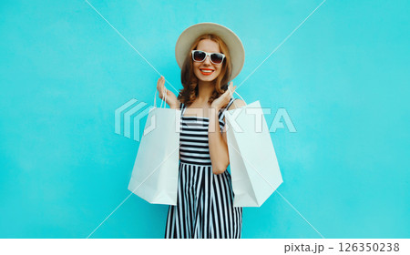 Stylish beautiful happy woman standing with colorful shopping bags posing on vivid blue wall 126350238
