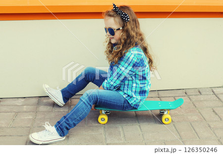 Stylish little girl child posing with skateboard on city street 126350246