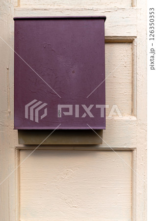 A purple mailbox mounted on a wooden door in a quaint residential area during the daytime A purple mailbox mounted on a wooden door in a quaint residential area during the daytime 126350353