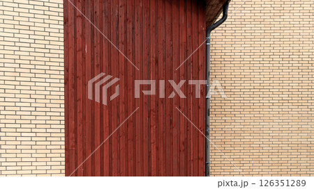 Wooden wall panel contrasting with brick facade of building during daytime exterior view 126351289