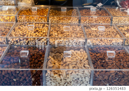Assorted nuts displayed in clear containers at a market stall in the late afternoon Assorted nuts displayed in clear containers at a market stall in the late afternoon 126351483