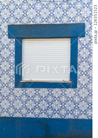 Decorative blue and white tiled wall with a closed window in a residential building 126351523