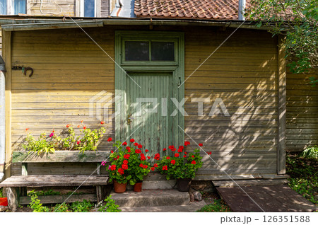 Charming wooden house entrance with blooming flowers in pots on a sunny day 126351588