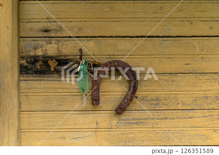 Horseshoe hanging on a weathered wooden wall at a rustic barn during daylight hours 126351589