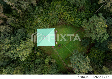 Aerial view of a observation tower cabin surrounded by dense forest greenery in a tranquil setting Aerial view of a observation tower cabin surrounded by dense forest greenery in a tranquil setting 126351747