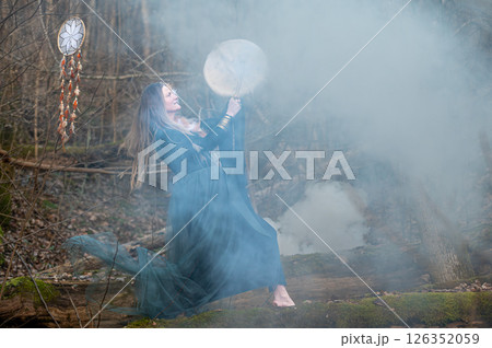 Woman playing drum in foggy forest. Shallow depth of feld 126352059