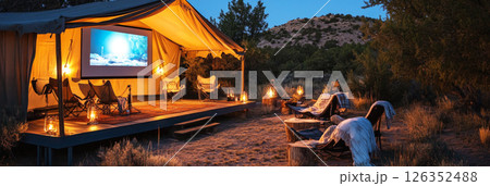 Glamping in style with a projector movie, guests lounging with blankets and popcorn, creating a cozy, relaxed atmosphere under the cool night sky in the wilderness, banner 126352488