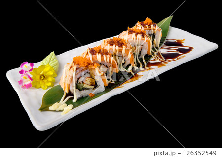 Spicy sushi roll with dual sauce and floral garnish on white plate 126352549