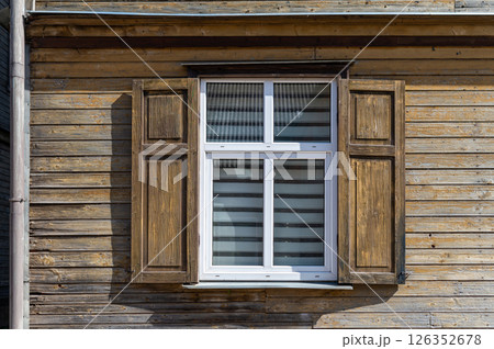 The wooden shutters of a window are wide open, revealing a bright, cheerful interior. 126352678