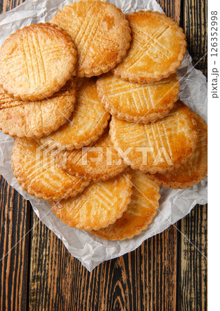 French Sables Bretons Cookies, or French Salted Butter Cookies closeup on parchment paper on wooden table. Vertical top view 126352998