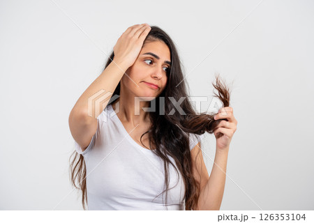 A young, beautiful but sad woman on a white background because her hair is unkempt and broken 126353104