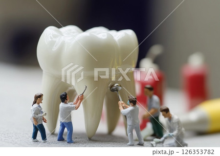 Miniature doctors treat a giant tooth in a dental clinic setup for educational purposes 126353782