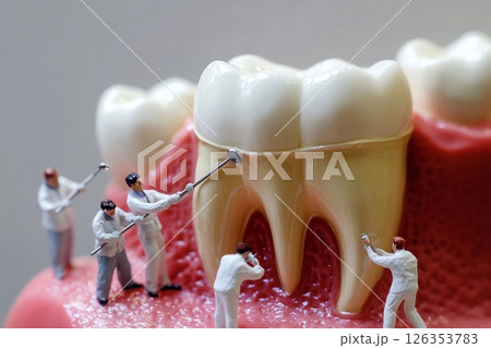Miniature doctors treat a giant tooth in a dental clinic setup for educational purposes 126353783