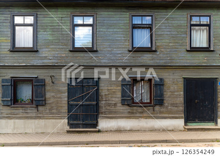 Old wooden house with rustic shutters and weathered facade in a quiet neighborhood on a sunny day 126354249