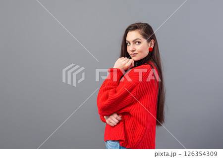 headshot of a happy emotional teenage girl with long hair dressed in a red sweater and jeans 126354309
