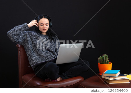 focused young freelance woman sitting with laptop and headphones, working remotely online from home focused young freelance woman sitting with laptop and headphones, working remotely online from home 126354400