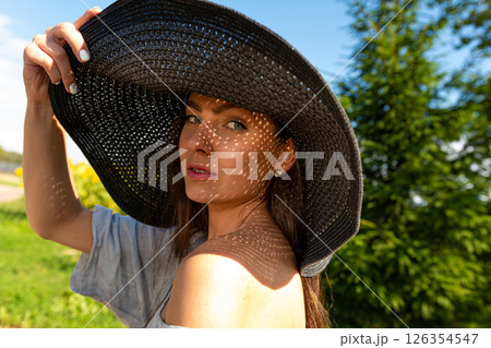 closeup portrait of woman in elegant hat enjoying summer sun, pattern of shadows falling on her face 126354547
