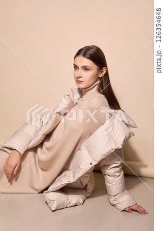 beautiful fashion female model in beige down jacket and long wool turtleneck dress in studio. Autumn winter total fashion beige look beautiful fashion female model in beige down jacket and long wool turtleneck dress in studio. Autumn winter total fashion beige look 126354648
