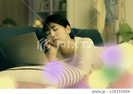 夜ソファでノートパソコンを見ながら寝落ちする若い女性 126355004