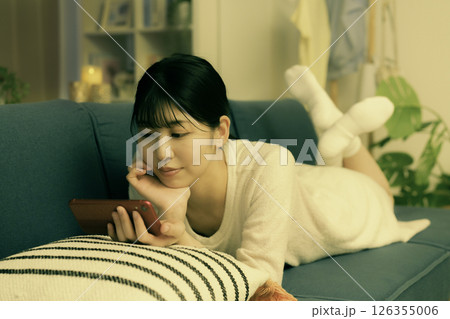 夜ソファでスマホを見る若い女性 夜ソファでスマホを見る若い女性 126355006