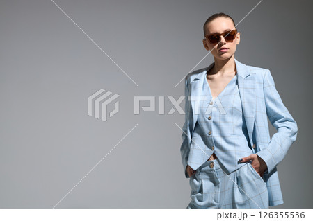 High fashion portrait of young confident female model in blue three-piece suit. Monochrome blue outfit High fashion portrait of young confident female model in blue three-piece suit. Monochrome blue outfit 126355536