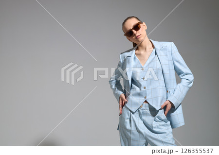 High fashion portrait of young confident female model in blue three-piece suit. Monochrome blue outfit High fashion portrait of young confident female model in blue three-piece suit. Monochrome blue outfit 126355537