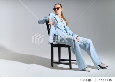 High fashion portrait of young confident female model in blue three-piece suit. Monochrome blue outfit High fashion portrait of young confident female model in blue three-piece suit. Monochrome blue outfit 126355540