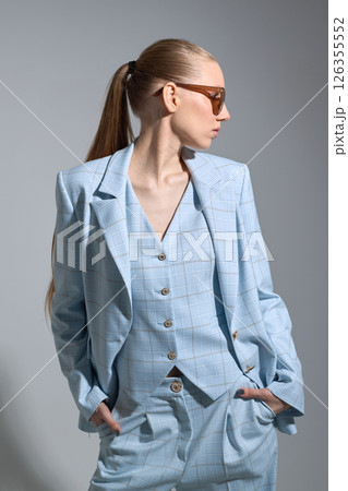 High fashion portrait of young confident female model in blue three-piece suit. Monochrome blue outfit High fashion portrait of young confident female model in blue three-piece suit. Monochrome blue outfit 126355552