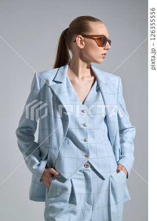 High fashion portrait of young confident female model in blue three-piece suit. Monochrome blue outfit 126355556