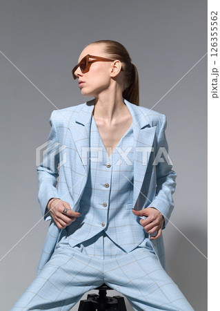 High fashion portrait of young confident female model in blue three-piece suit. Monochrome blue outfit High fashion portrait of young confident female model in blue three-piece suit. Monochrome blue outfit 126355562