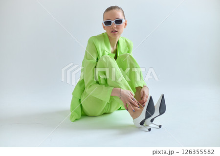 High fashion portrait of young confident female model in green lime color three-piece suit. Monochrome green outfit High fashion portrait of young confident female model in green lime color three-piece suit. Monochrome green outfit 126355582