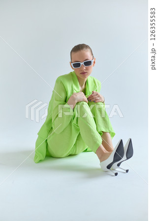 High fashion portrait of young confident female model in green lime color three-piece suit. Monochrome green outfit High fashion portrait of young confident female model in green lime color three-piece suit. Monochrome green outfit 126355583