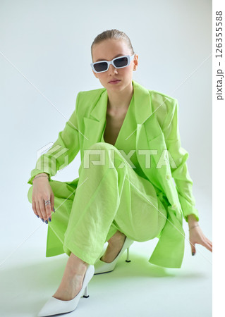 High fashion portrait of young confident female model in green lime color three-piece suit. Monochrome green outfit High fashion portrait of young confident female model in green lime color three-piece suit. Monochrome green outfit 126355588