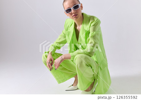 High fashion portrait of young confident female model in green lime color three-piece suit. Monochrome green outfit 126355592