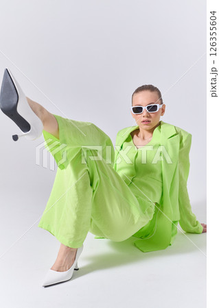 High fashion portrait of young confident female model in green lime color three-piece suit. Monochrome green outfit High fashion portrait of young confident female model in green lime color three-piece suit. Monochrome green outfit 126355604