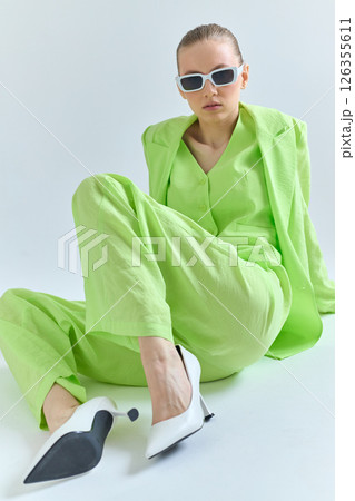 High fashion portrait of young confident female model in green lime color three-piece suit. Monochrome green outfit High fashion portrait of young confident female model in green lime color three-piece suit. Monochrome green outfit 126355611