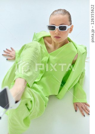 High fashion portrait of young confident female model in green lime color three-piece suit. Monochrome green outfit High fashion portrait of young confident female model in green lime color three-piece suit. Monochrome green outfit 126355622