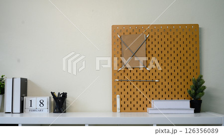 Minimalist home office shelf with pegboard, books, stationery, and indoor plants 126356089