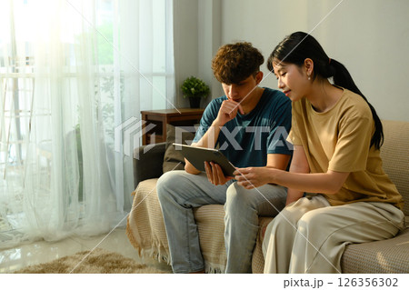 Man and woman thoughtfully looking at digital tablet, planning or reviewing content Man and woman thoughtfully looking at digital tablet, planning or reviewing content 126356302