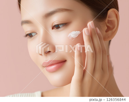 スキンケアで顔に保湿クリームを塗る日本人女性の手元 126356844